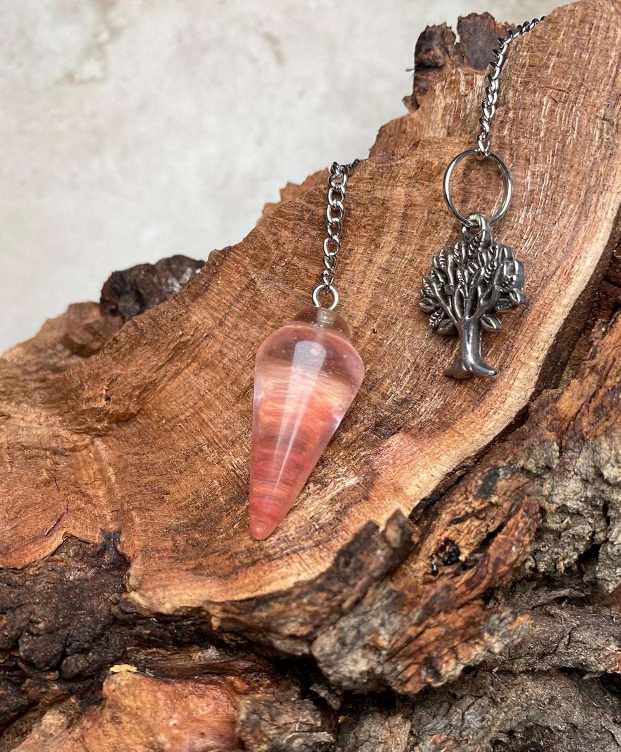 Pink faceted teardrop pendulum bag charm with silver-tone tree charm and chain.
