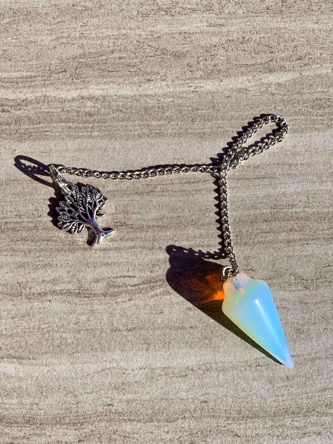 Blue opalescent teardrop pendulum with tree charm on gold-tone chain