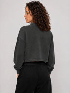 Dark gray cropped sweatshirt, back view with long sleeves and ribbed cuffs