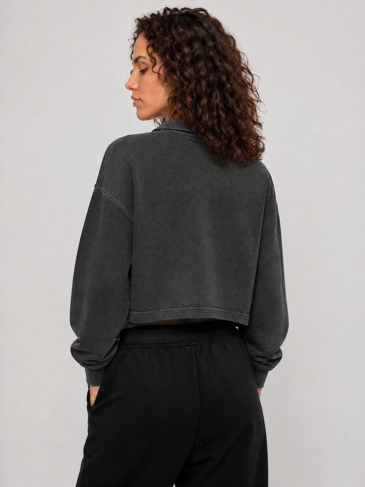 Dark gray cropped sweatshirt, back view with long sleeves and ribbed cuffs