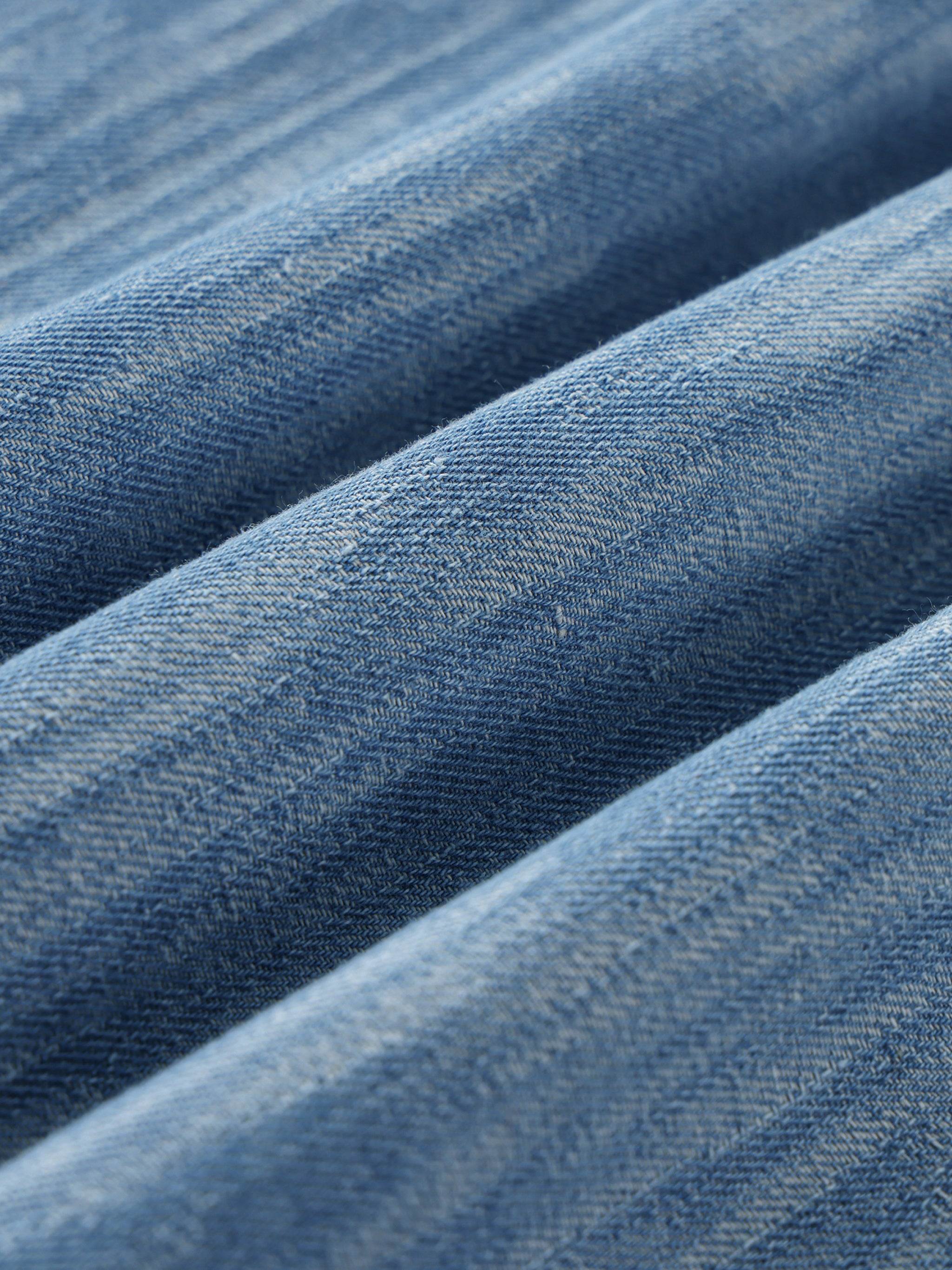 Blue distressed fabric close-up with visible woven texture and washed pattern