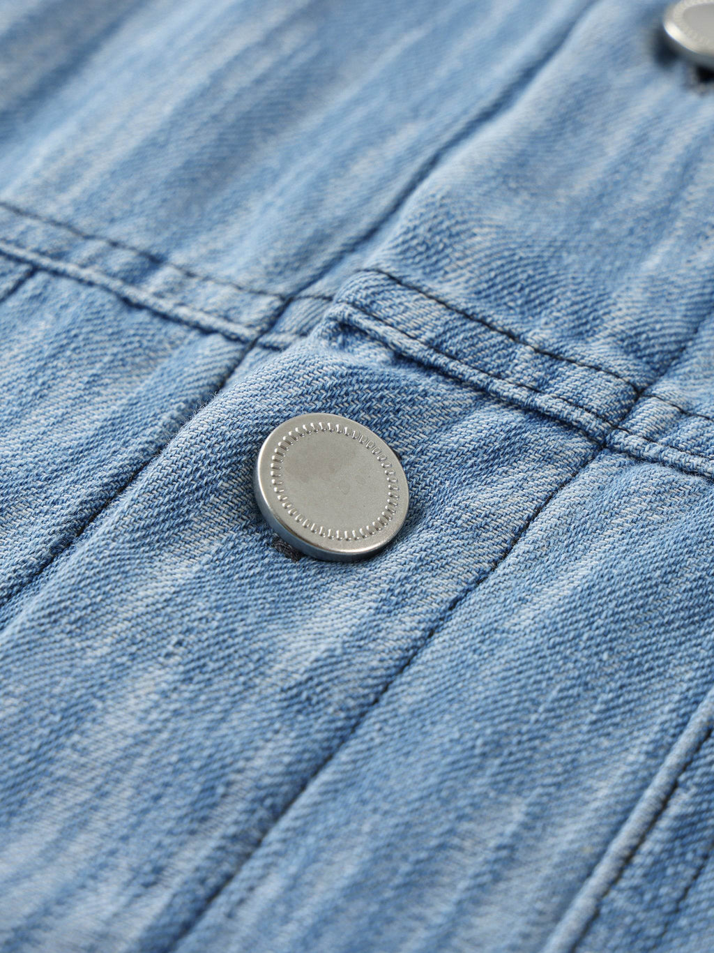 Blue distressed shirt close-up of metal button with cross-stitch placket