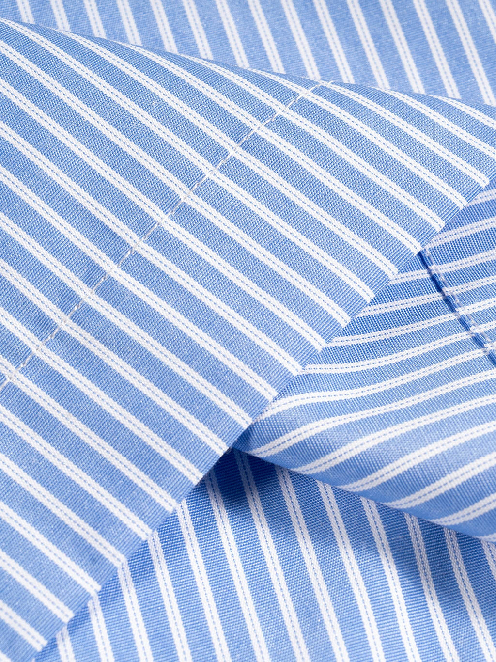 Blue-and-white vertical stripe shirt fabric close-up with curved seam