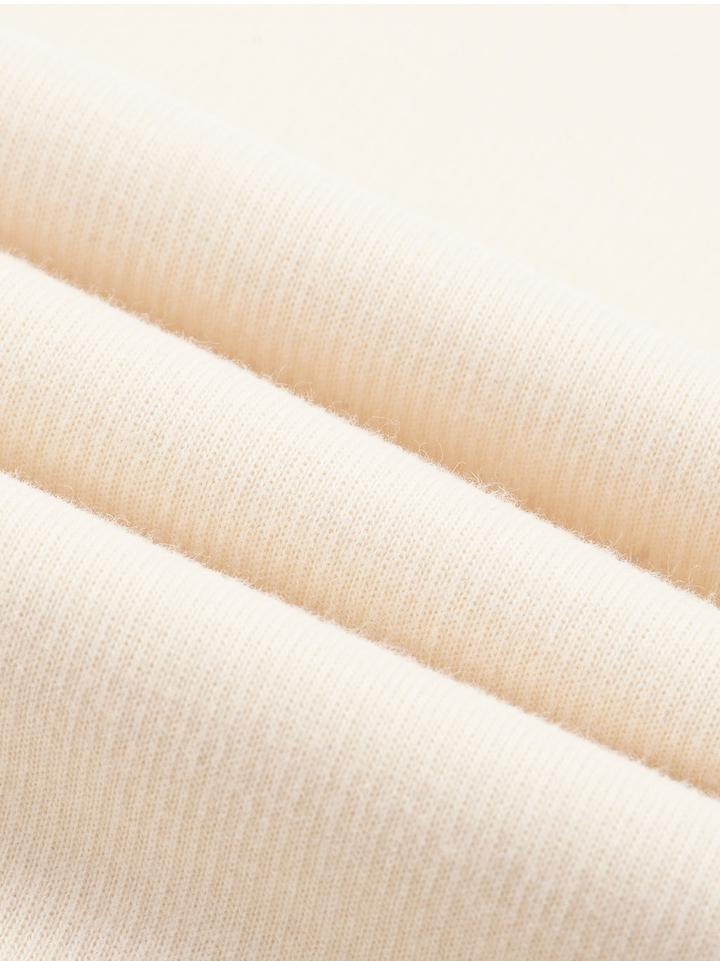 Cream knit fabric close-up showing fine row texture and smooth drape