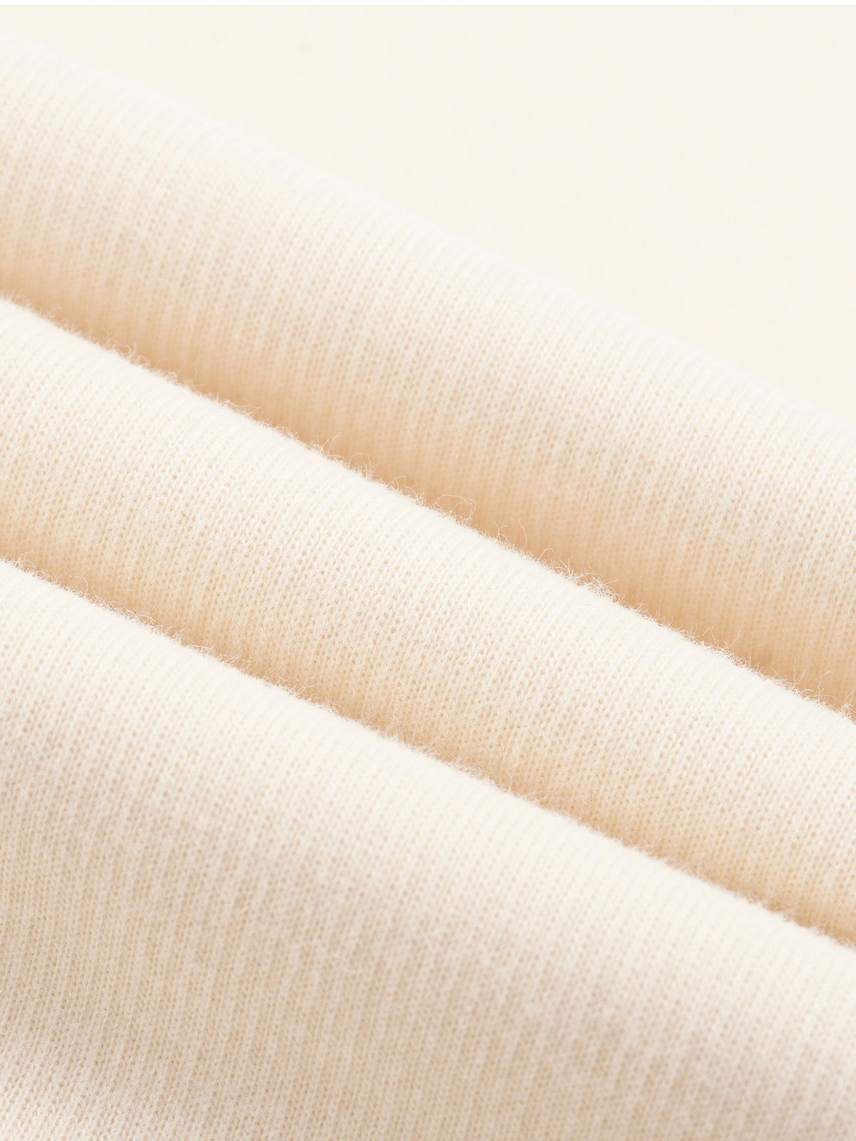 Cream knit fabric close-up showing fine row texture and smooth drape