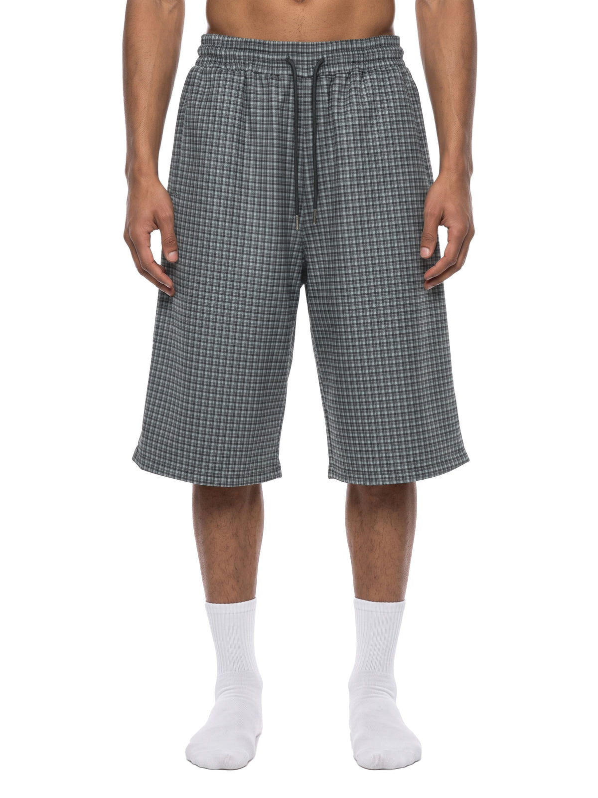 Navy blue plaid drawstring shorts on model, showing elastic waist and knee-length fit