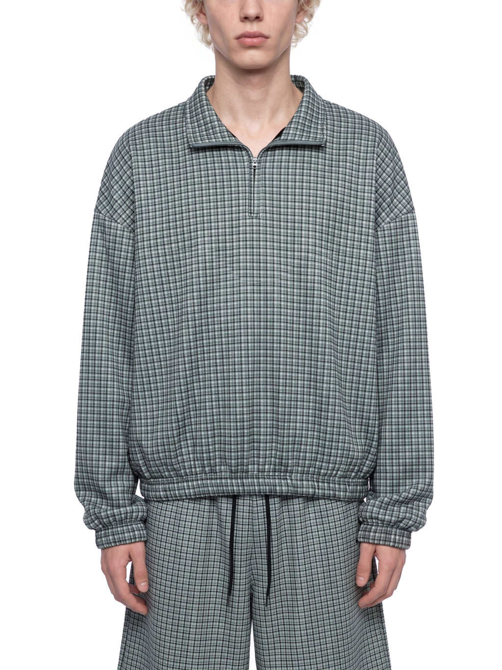 Mens plaid quarter-zip sweatshirt in dark green, worn front view, model torso