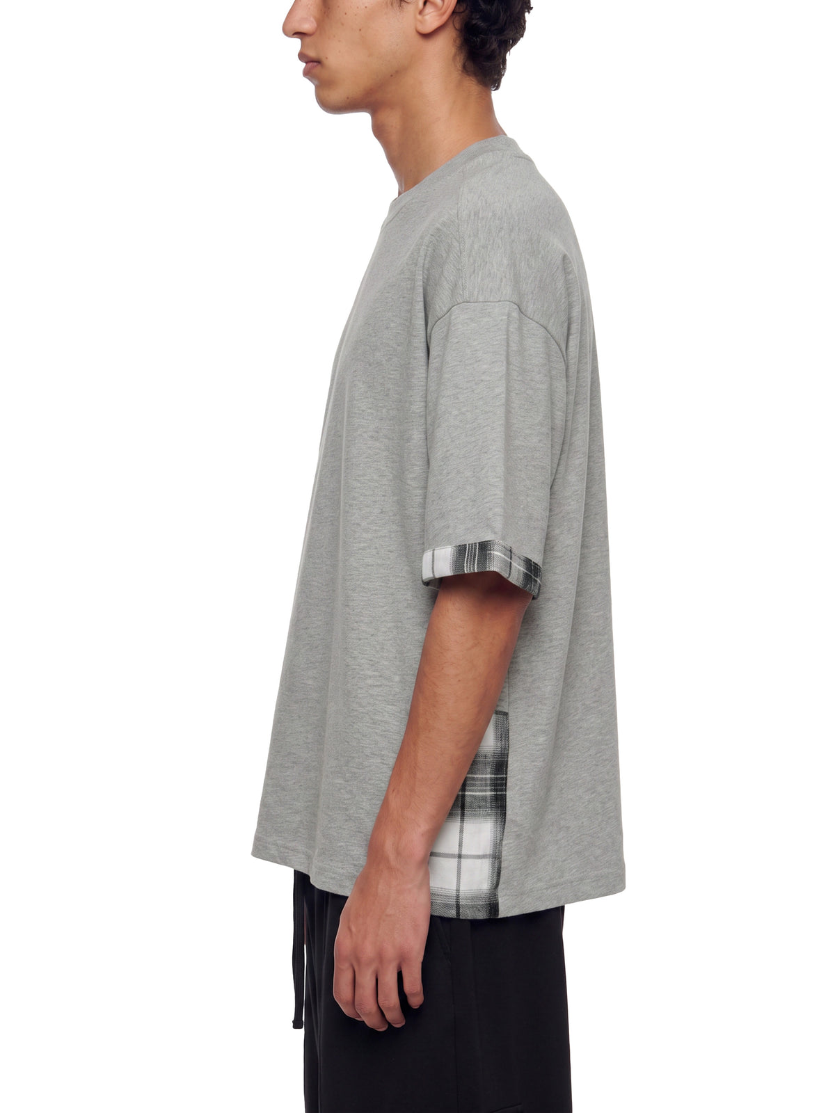 Gray unisex T-shirt on model, side view with plaid cuffed sleeves