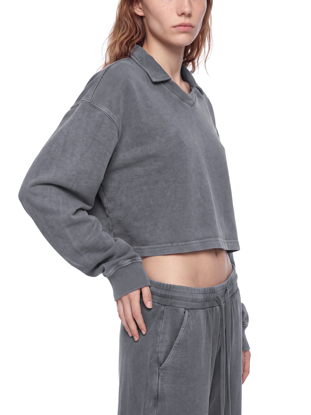 Model wearing a gray vintage wash crop sweatshirt, angled side view with ribbed cuffs