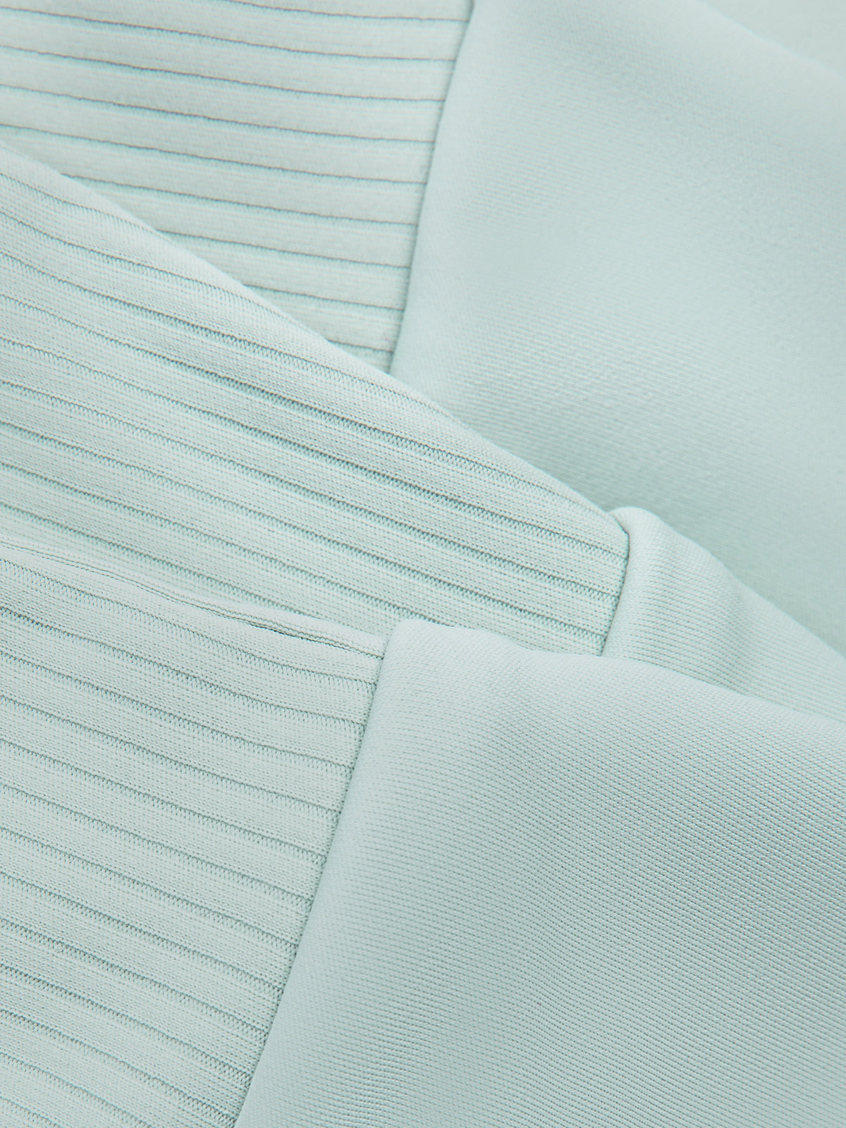 Mint green crop tank top fabric close-up with fine ribbed knit and seam stitching.