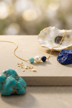 Gold beaded necklace with white pearl and green and dark blue stones