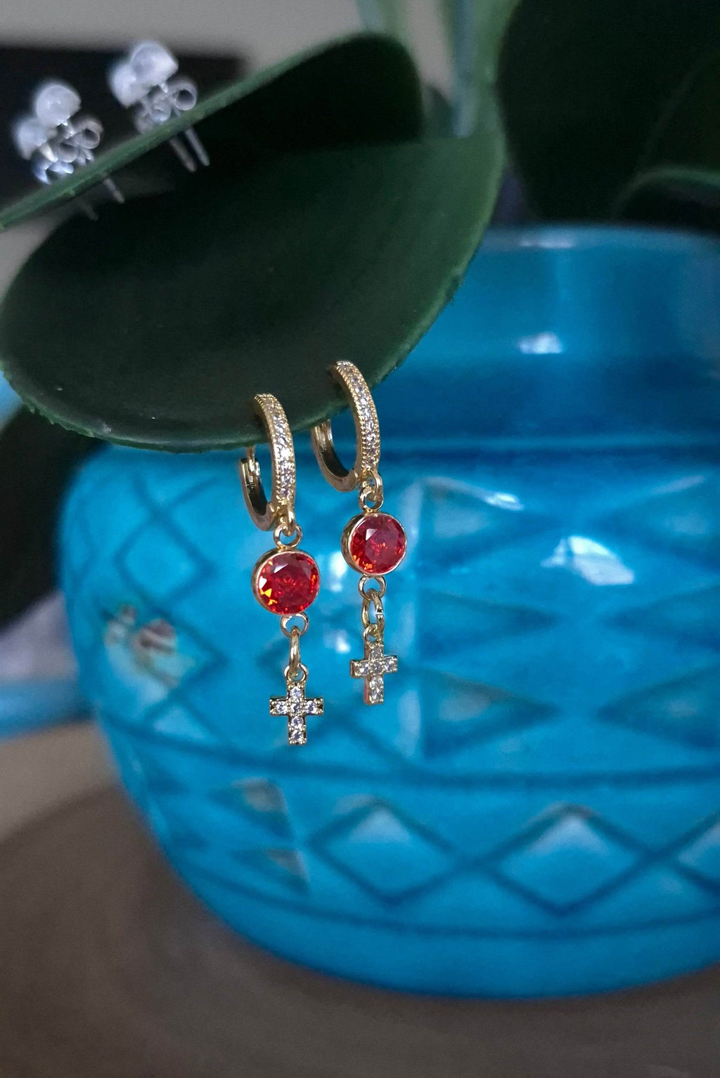 Gold-tone hoop earrings with red drop stones and small cross charms