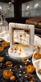 Gold-tone earrings with orange teardrop stone and white zircon accents on stand